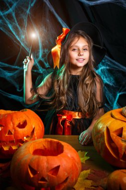 Halloween cadı kavramı - küçük cadı çocuk zevk örümcek ağı üzerinde sihirli değnek ile ve eğri kabaklar arka plan ile oynama.