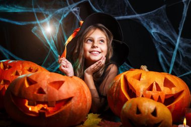 Halloween cadı kavramı - küçük cadı çocuk zevk örümcek ağı üzerinde sihirli değnek ile ve eğri kabaklar arka plan ile oynama.