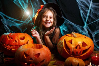 Halloween cadı kavramı - küçük cadı çocuk zevk örümcek ağı üzerinde sihirli değnek ile ve eğri kabaklar arka plan ile oynama.
