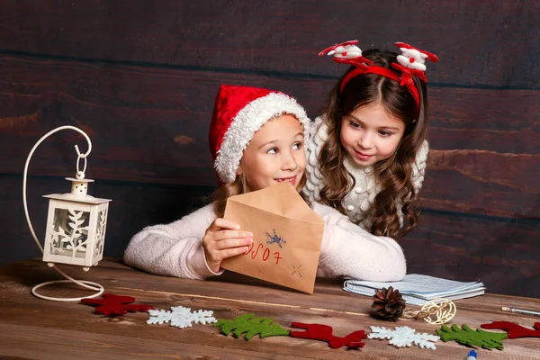 Child writes letter to Santa Claus . Funny little girls in Santa hat writes letter to Santa