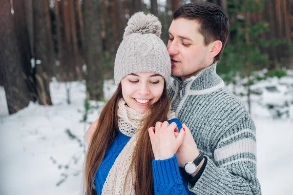 Jovem casal abraçando e beijando na floresta no inverno . — Fotografia de Stock