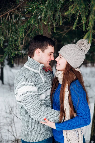 Jovem casal abraçando e beijando na floresta no inverno . — Fotografia de Stock