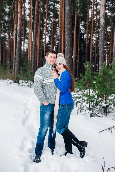 Jovem casal abraçando e beijando na floresta no inverno . — Fotografia de Stock