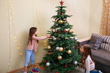 Mutlu Noeller ve mutlu tatiller. İki sevimli küçük kız ev oda, Noel ağacı süsleme.