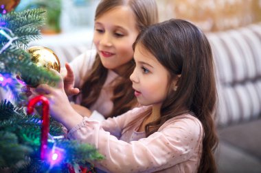 Mutlu Noeller ve mutlu tatiller. İki sevimli küçük kız ev oda, Noel ağacı süsleme.