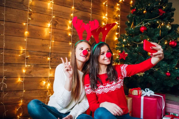 Χαμογελώντας φίλες λαμβάνοντας μια selfie με smarphone. Χριστουγεννιάτικη διάθεση. — Φωτογραφία Αρχείου