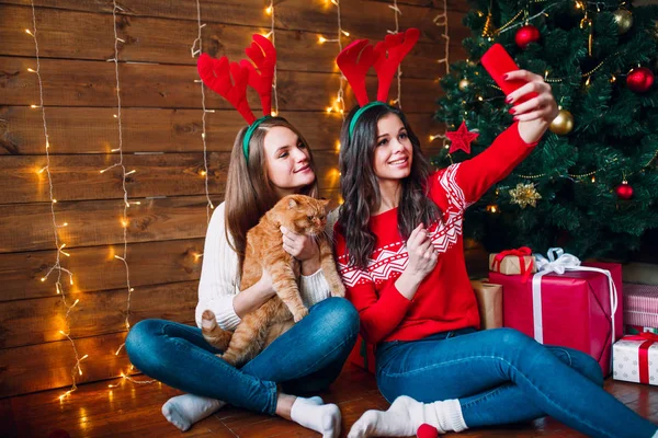 Mosolyogva vesz egy selfie-val smarphone barátnők. Karácsonyi hangulatban. — Stock Fotó