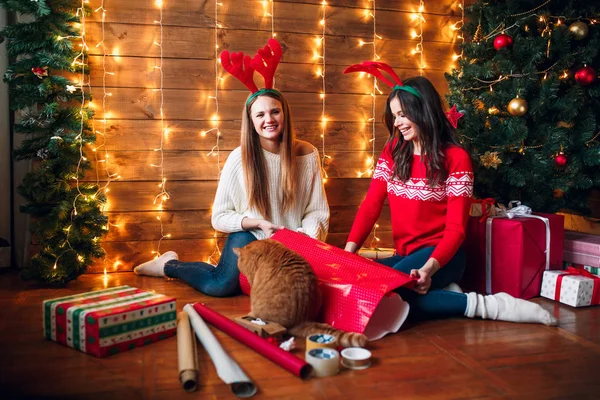 Φίλοι περιτυλίγματος και διακόσμησης δώρο κοντά στο χριστουγεννιάτικο δέντρο — Φωτογραφία Αρχείου