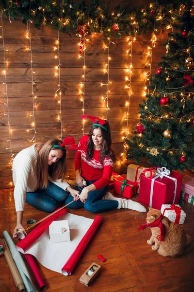 Φίλοι περιτυλίγματος και διακόσμησης δώρο κοντά στο χριστουγεννιάτικο δέντρο — Φωτογραφία Αρχείου
