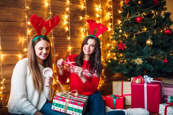 Όμορφες αδερφές περιτυλίγματος και διακόσμησης δώρο κοντά στο χριστουγεννιάτικο δέντρο — Φωτογραφία Αρχείου