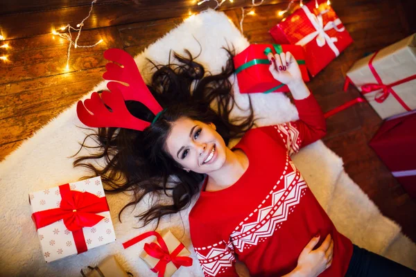 Mujer con luces navideñas y regalos tirados en el suelo. Feliz Navidad y Feliz Año Nuevo — Foto de Stock