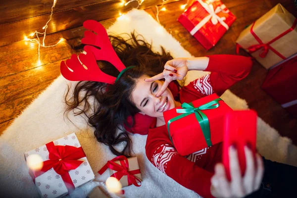 Mujer con luces navideñas y regalos tirados en el suelo — Foto de Stock
