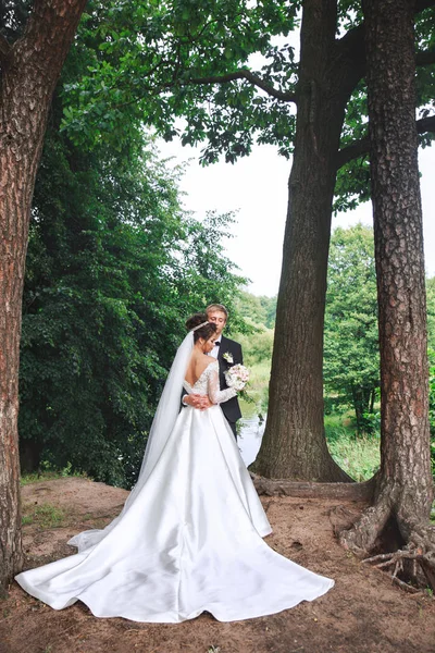 Mooie bruidspaar in park. Bruid en bruidegom omhelzen elkaar buiten — Stockfoto