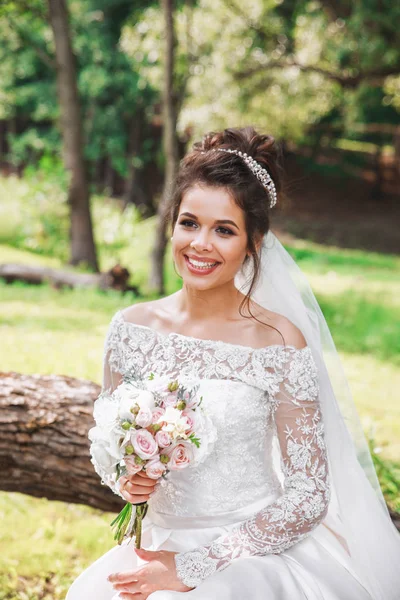 Hermosa novia feliz con ramo de flores en el parque — Foto de Stock