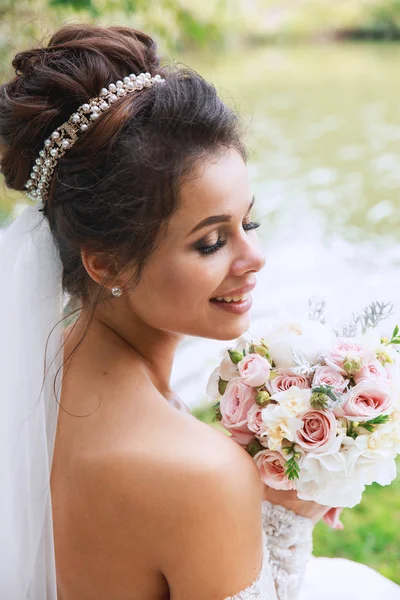 Svatební den. Mladá krásná nevěsta s účes a make-up pózuje v bílé šaty a závoj. — Stock fotografie