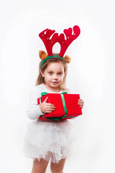 Bebé de Navidad en cuernos de ciervo sosteniendo una caja de regalo roja sobre fondo blanco. Tiempo de Navidad —  Fotos de Stock