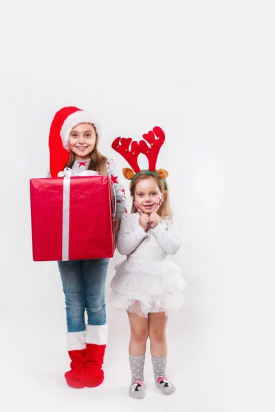 Dos niños sonrientes felices en el sombrero de Santa y cuernos de ciervo con una gran caja de regalo de Navidad y dulces. Tiempo de Navidad —  Fotos de Stock