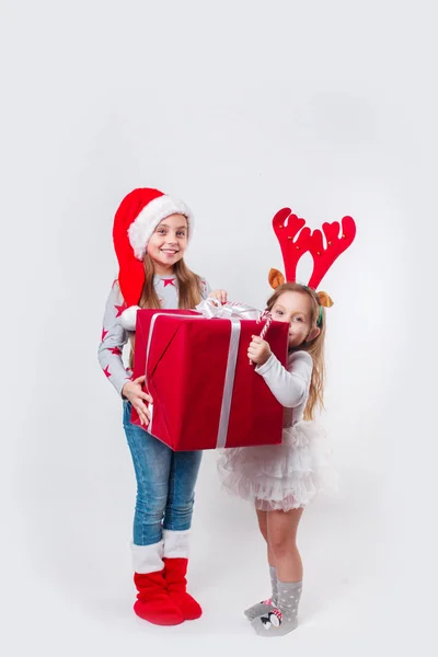 Dos niños sonrientes felices en el sombrero de Santa y cuernos de ciervo con una gran caja de regalo de Navidad y dulces. Tiempo de Navidad —  Fotos de Stock