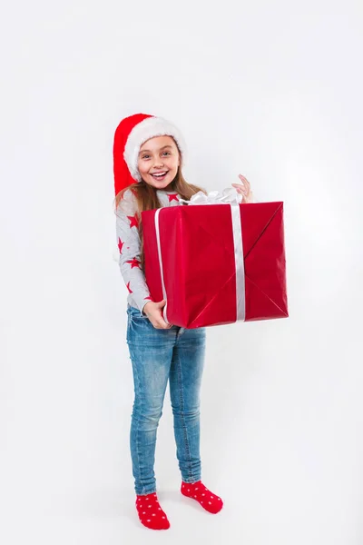 Sonriente niño divertido en Santa sombrero rojo con regalo de Navidad en la mano. Concepto de Navidad. —  Fotos de Stock