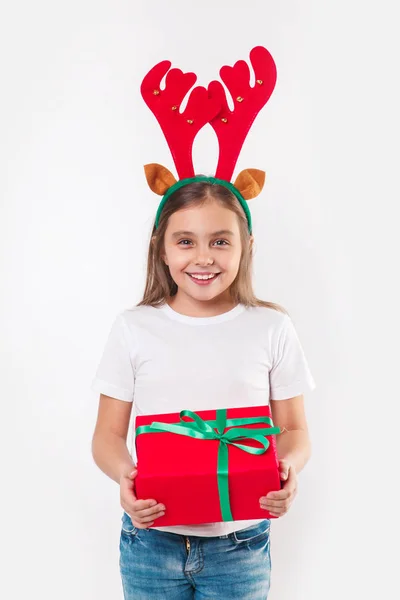 Ребенок в оленьих рогах с рождественской подарочной коробкой в руке на белом фоне. Концепция Рождества . — стоковое фото