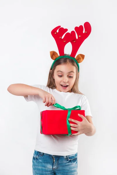 Ребенок в оленьих рогах с рождественской подарочной коробкой в руке на белом фоне. Концепция Рождества . — стоковое фото