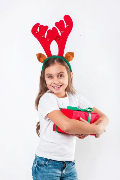 Niño en cuernos de ciervo sosteniendo la caja de regalo de Navidad en la mano sobre fondo blanco. Concepto de Navidad . —  Fotos de Stock