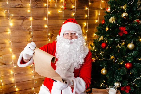 산타 클로스 크리스마스 나무와 큰 자루 근처 집에서 자신의 방에 앉아 고 크리스마스 편지를 읽거나 위시 리스트의 초상화 — 스톡 사진