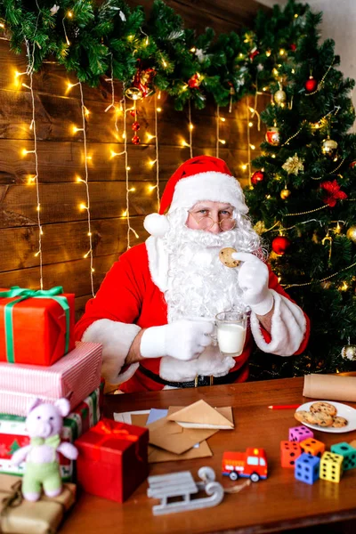 Joyeux Noël et Joyeuses Fêtes. Santa Clause prépare des cadeaux pour les enfants pour Noël au bureau à la maison . — Photo