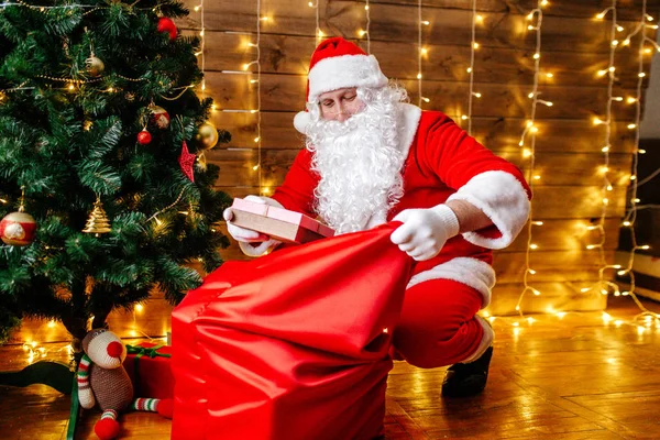 Santa Claus poblíž vánoční stromeček s dárky. Vánoční čas — Stock fotografie