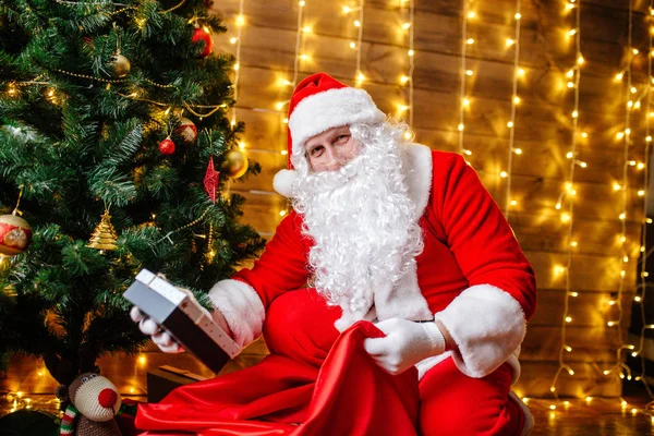 Santa Claus poblíž vánoční stromeček s dárky. Vánoční čas — Stock fotografie