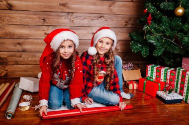 Santa şapkalar paketi hediyeler Noel ağacı yakınındaki mutlu komik küçük kız