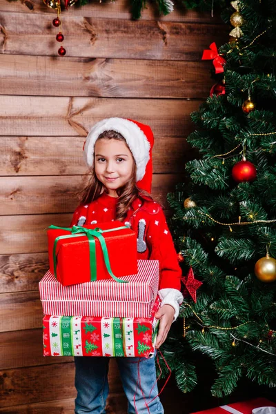 Милая маленькая девочка с подарочными коробками рядом с деревом дома . — стоковое фото