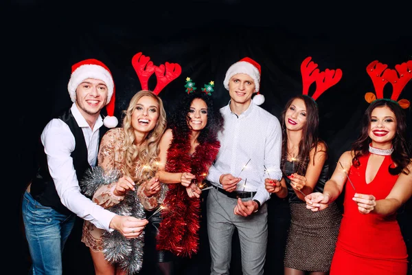 Festa com amigos. Eles adoram o Natal. Grupo de jovens alegres carregando brilhos e flautas de champanhe dançando na festa de ano novo e olhando feliz. Conceitos sobre o estilo de vida de união — Fotografia de Stock