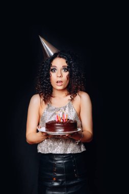 Doğum günü pastası mumlar ile siyah arka planda tutan genç güzel esmer kız portresi