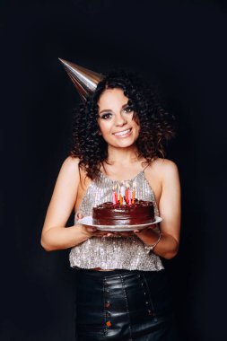 Doğum günü pastası mumlar ile siyah arka planda tutan genç güzel esmer kız portresi