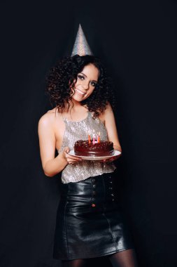 Doğum günü pastası mumlar ile siyah arka planda tutan genç güzel esmer kız portresi