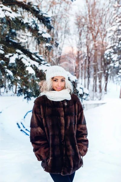 Ao ar livre perto retrato de jovem bela mulher elegante com cabelo afro, vestindo casaco de pele no parque de inverno. Moda de inverno, Natal feriados conceito . — Fotografia de Stock