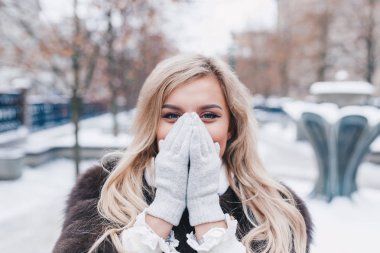 Havalı kürklü kışlık ceket giyen, karla kaplı sokakta poz veren güzel, modaya uygun, mutlu bir kızın açık hava portresi..