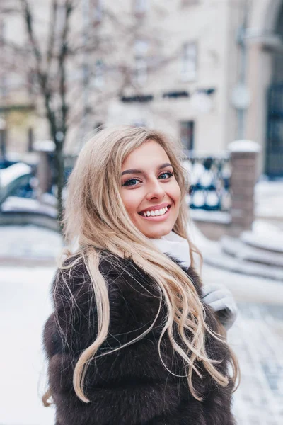 코트를 눈덮인 거리에 포즈를 취하고 행복하게 아름다운 소녀의 — 스톡 사진