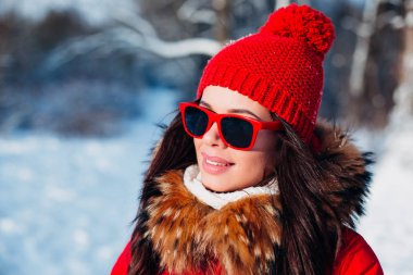 Kış arka plan üzerinde kırmızı güneş gözlüğü ile gülümseyen kadın