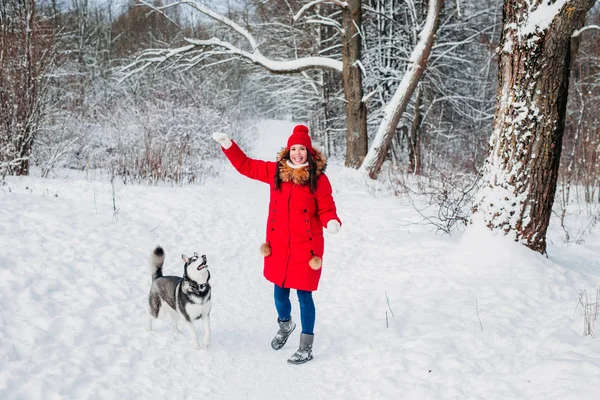 Jovem mulher brincando com seu cachorro Husky no parque de inverno — Fotografia de Stock