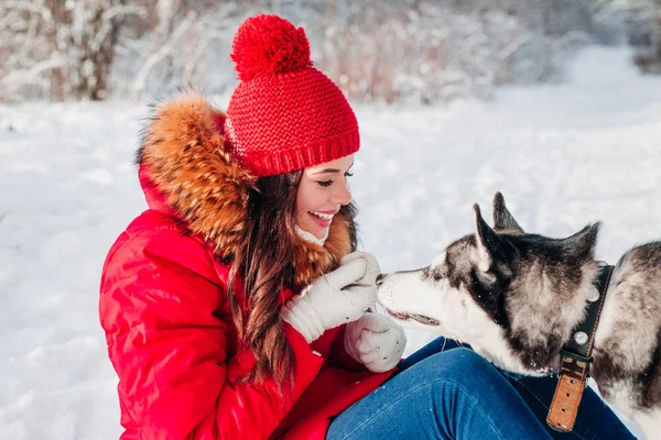 Jovem mulher brincando com seu cachorro Husky no parque de inverno — Fotografia de Stock