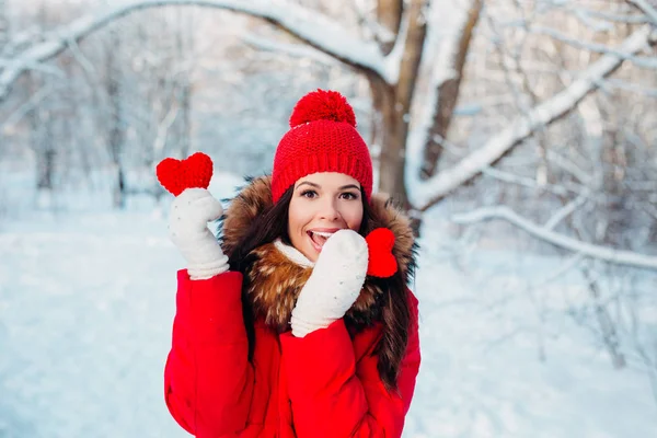 Hermosa joven sosteniendo un corazón rojo en las manos en el parque de invierno. Tiempo de invierno . —  Fotos de Stock