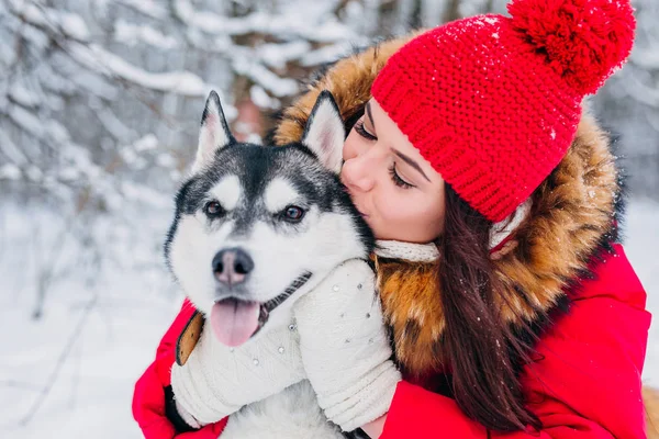 Kvinnan smeker Husky hunden i vinter skog — Stockfoto