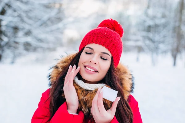 Retrato de invierno de una hermosa mujer con crema facial y copo de nieve en el fondo de invierno. Cuidado de la piel facial en invierno —  Fotos de Stock