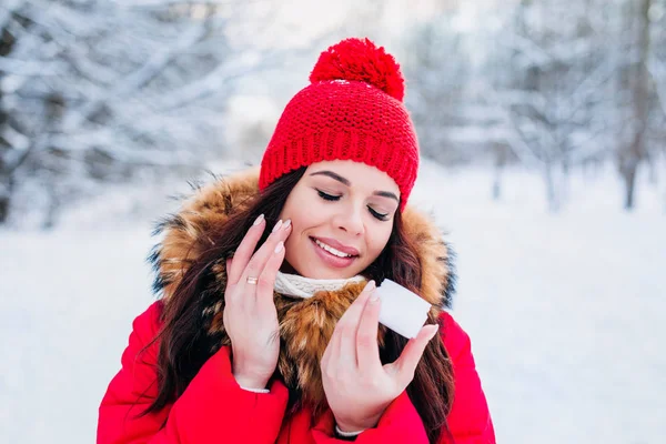 Retrato de invierno de una hermosa mujer con crema facial y copo de nieve en el fondo de invierno. Cuidado de la piel facial en invierno —  Fotos de Stock