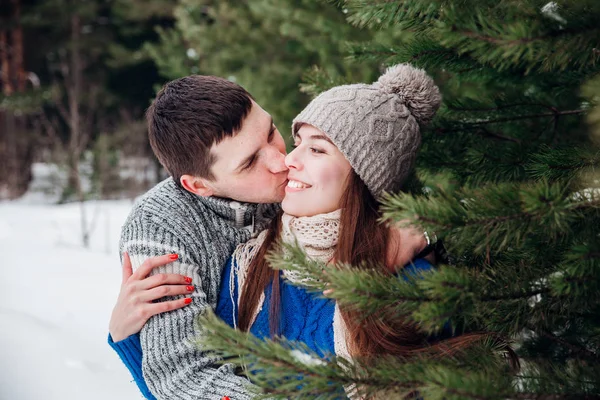 Щаслива пара обіймає і сміється на відкритому повітрі в зимовому лісі — стокове фото