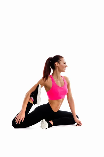 Unga fitness kvinna gör stretching hennes ben. Foto av muskulös kvinna i trendiga sportkläder på vit bakgrund. — Stockfoto