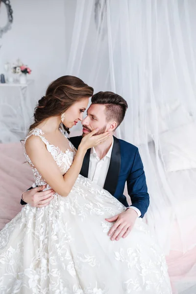 Bruidspaar knuffelen elkaar binnen. Mooi model meisje in witte jurk. Man in pak. Schoonheid bruid met de bruidegom. — Stockfoto