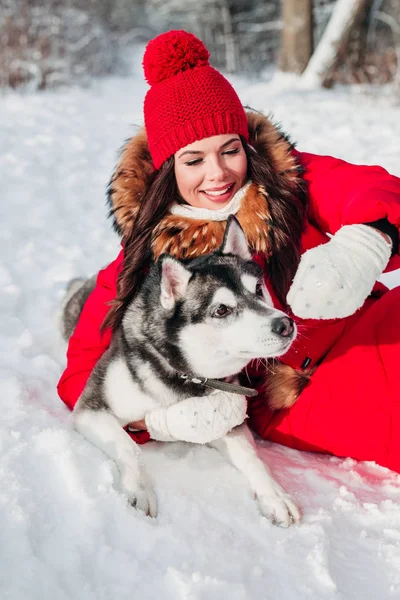 Ung kvinna leker med hennes Husky hunden i Vinterparken — Stockfoto